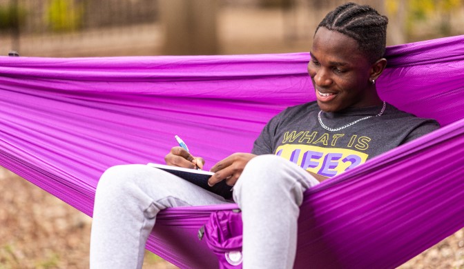 A Concordia University student studying in a hammock on campus